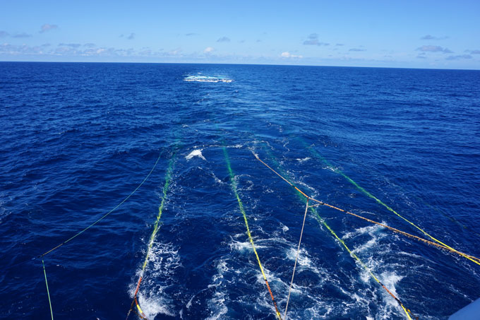 From the back of a boat, cables extend out into the sea.